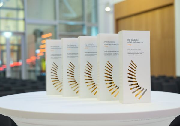 Die Trophys des Deutschen Arbeitsschutzpreises 2025 stehen auf einem Tisch, im Hintergrund der Veranstaltungssaal.
