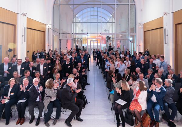 Applaudierendes Publikum im Veranstaltungssaal, die Nominierten stehend.
